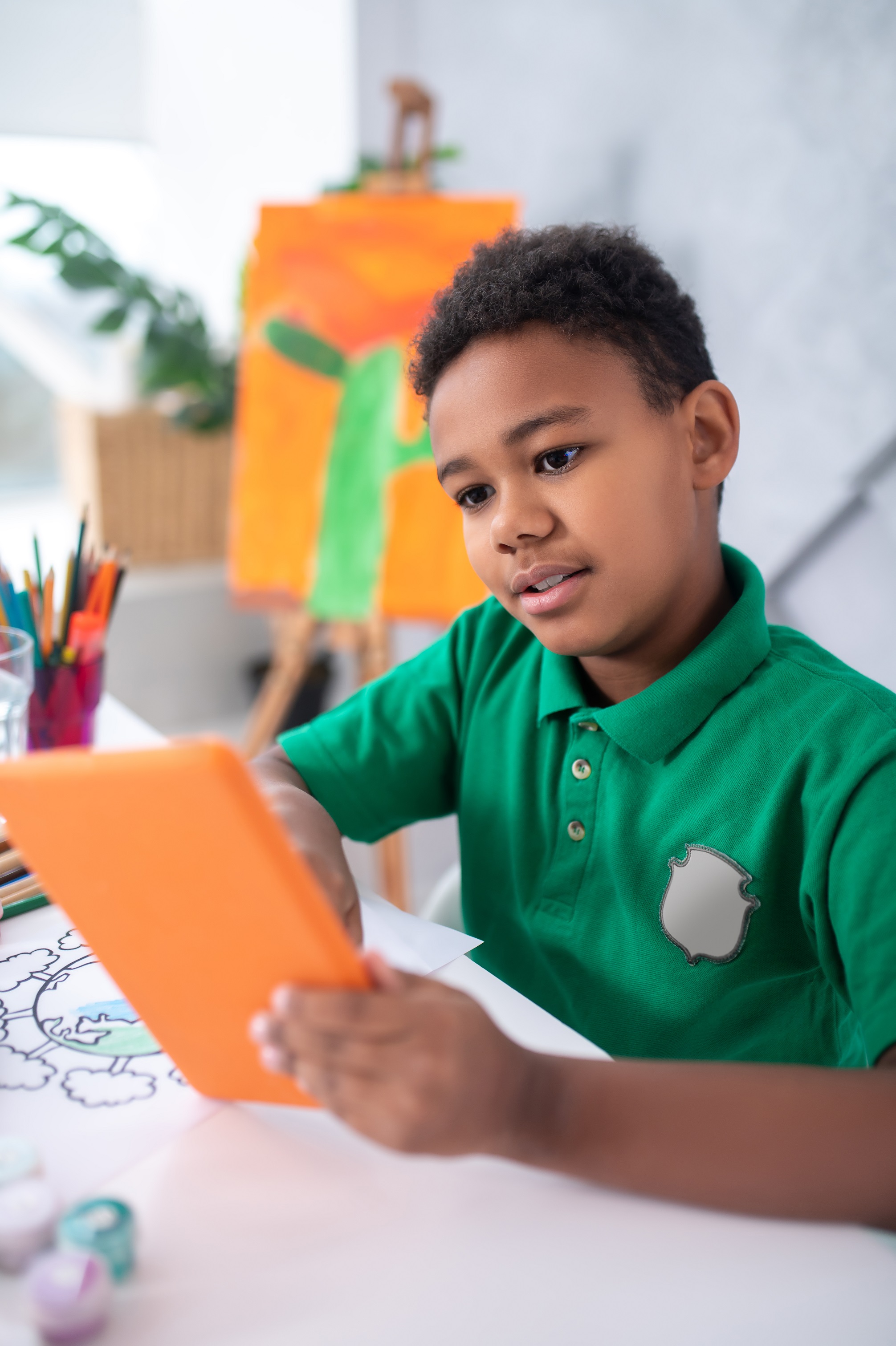 boy looking attentively tablet sitting table