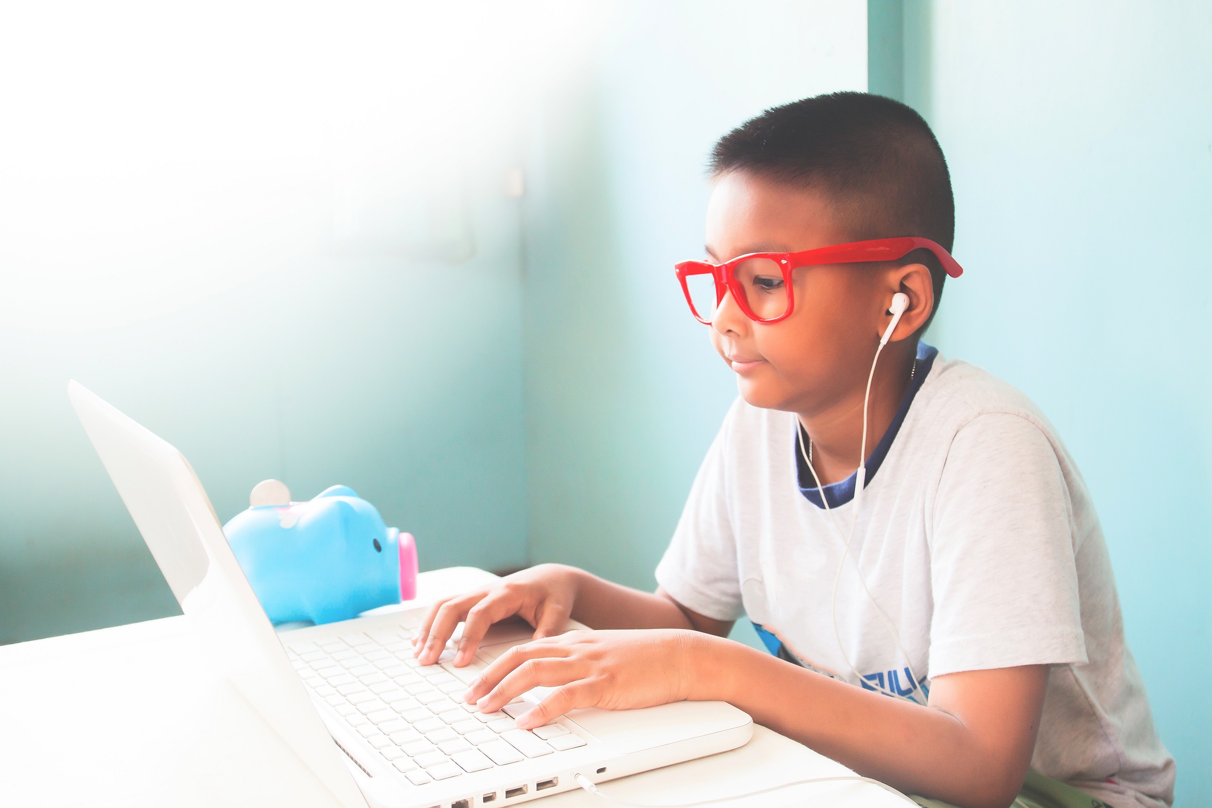 little boy child wearing red glasses listening using laptop computer